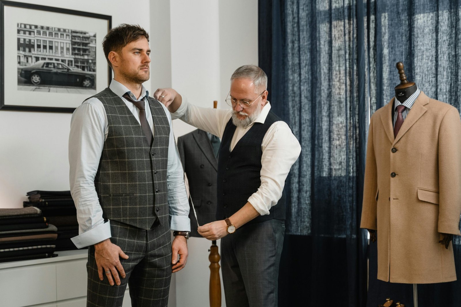 Tailor adjusts a client's suit in a classic atelier setting, emphasizing craftsmanship.