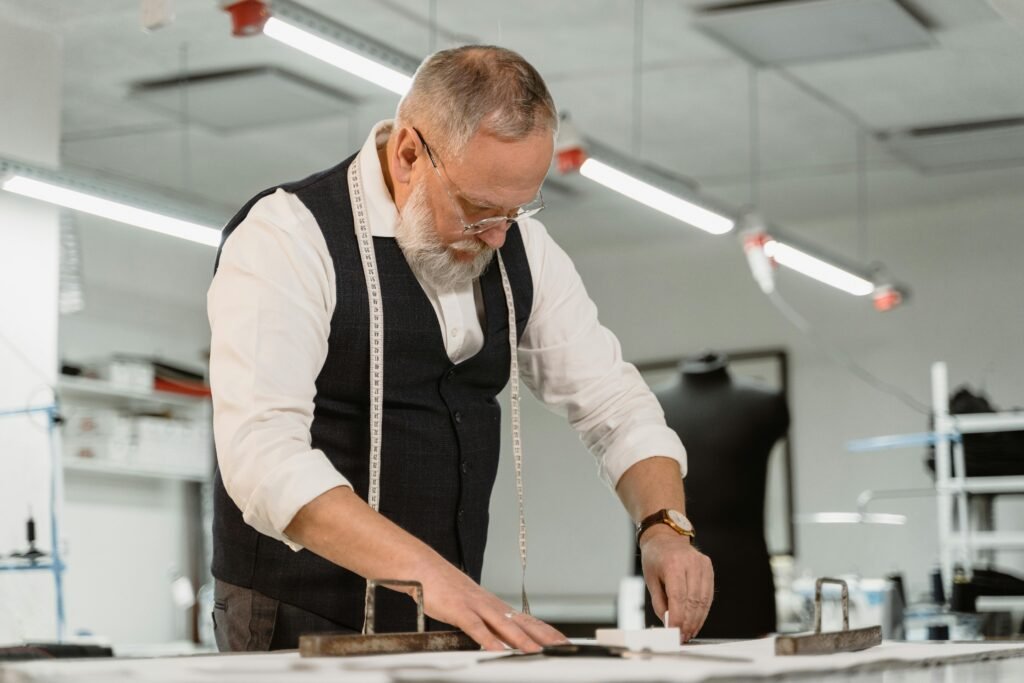 Experienced tailor measuring fabric in a bright fashion design studio.